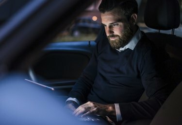 رجل أعمال يستخدم كمبيوتر محمول في السيارة ليلا