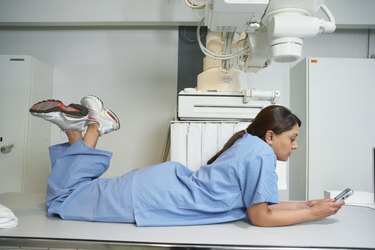 Indiase vrouwelijke verpleegster die op tafel ligt met behulp van mobiele telefoon