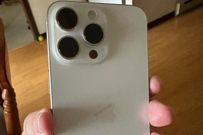החלק האחורי של ה-iPhone 15 Pro Max, מוחזק ביד של מישהו.