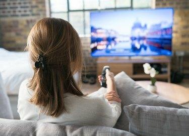 Nő otthon tévét néz