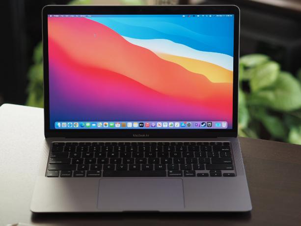 Apple M1 MacBook Air odprt na mizi z rastlinami v ozadju.