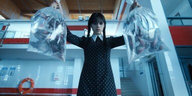 Jenna Ortega jako Wednesday Addams trzyma dwie torby wypełnione piraniami.