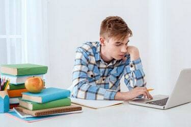 Милый молодой студент, использующий ноутбук