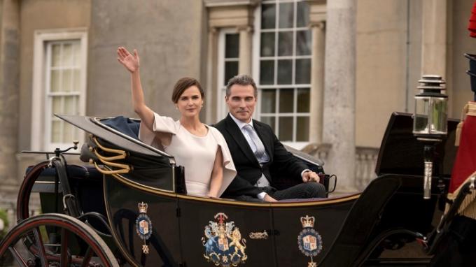 Kate y Hal en un carruaje, ella saludando con un vestido y él sonriendo en una escena de The Diplomat en Netflix.