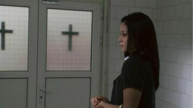 2012 年の映画「The Devil Inside」で、2 つのドアの前に立つ若い女性。