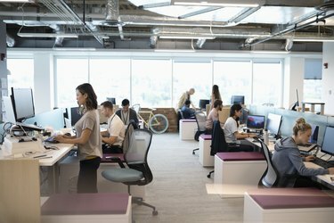 رجال أعمال مبدعون يعملون على أجهزة الكمبيوتر في مكتب مفتوح