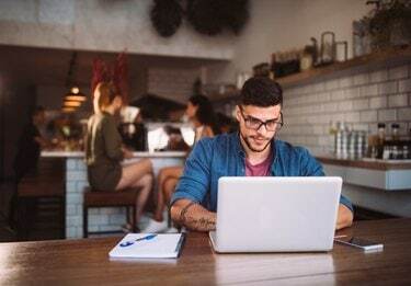 Giovane uomo d'affari hipster che lavora al computer portatile presso la caffetteria urbana