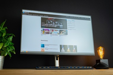 Dell 32 4K USB-C Hub-bildskärm som sitter på skrivbordet bredvid växt och ljus.