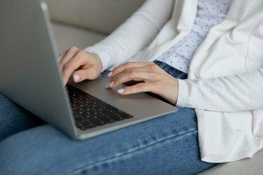 Naine paneb sülearvuti sülle, et teha kaugtööd, lähivõte