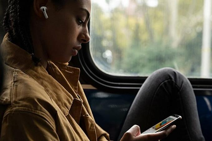 Uma pessoa sentada em um trem usando o novo Apple AirPods Pro enquanto olha para um telefone.