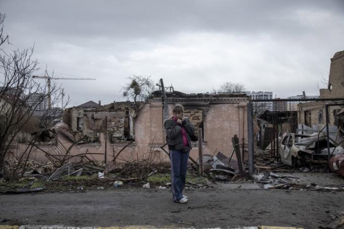 Lors des attaques russes contre l’Ukraine en 2022, une femme se tient debout dans les décombres en parlant au téléphone.