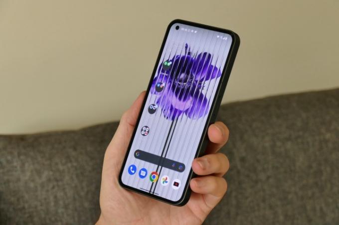 Nothing Phone 1 trzymany w dłoni, pokazujący tapetę Nothing.