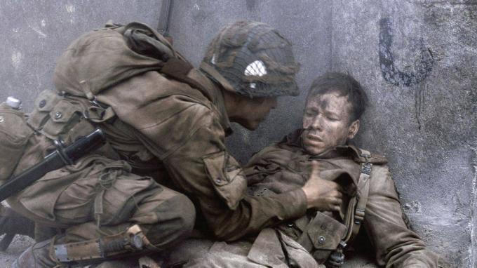 Um soldado verifica seu camarada ferido no Band of Brothers.