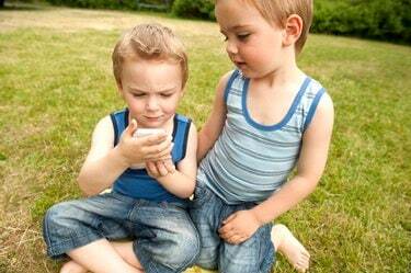 Tweelingbroers kijken naar mobiele telefoon in park