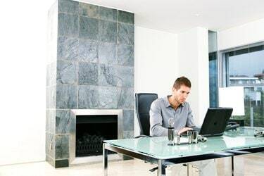 Vyras naudojasi nešiojamuoju kompiuteriu namų biure