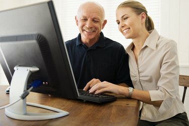 Femme aidant l'homme avec l'ordinateur