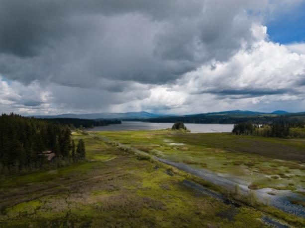 En mose og sø under en stormfuld himmel.