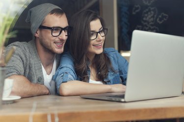 Pasangan bergaya dengan laptop kontemporer di kafe