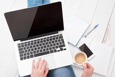 אישה עובדת בבית במחשב נייד עם כוס קפה