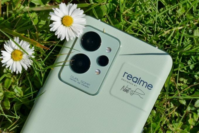 ה-.Realme GT 2 Pro מונח בדשא ליד פרחים