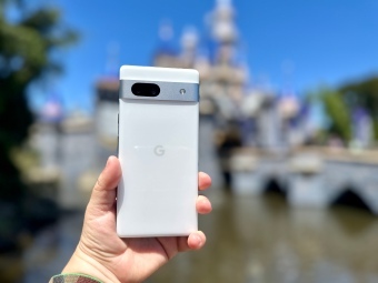 Google Pixel 7a ممسوكًا بيده أمام قلعة ديزني لاند