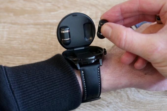 En person som tar frem ørepluggene til Huawei Watch Buds.