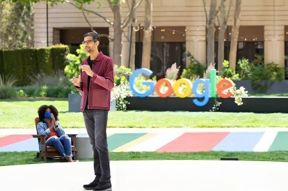 Sundar Pichai a Google logója előtt áll a Google IO 2021 kiállításon.