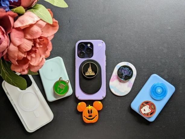 iPhone 14 Pro med Speck MagSafe Presidio Grip-fodral på, med en svart PopSocket MagSafe med Walt Disney World 50th Celebration PopSocket, tillsammans med en samling MagSafe-batteripaket och PopTops.