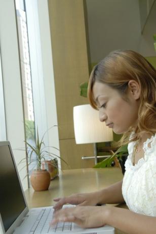 אישה צעירה משתמשת במחשב נייד בבית קפה, תנועה מטושטשת