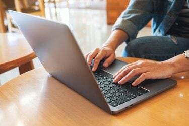 egy nő dolgozik, és gépel a laptop számítógép billentyűzetén az asztalon