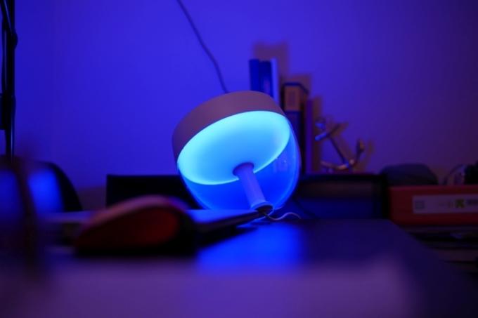 파란색으로 빛나는 필립스 Hue Iris 테이블 램프.