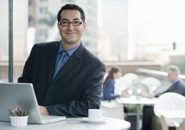 Glimlachende zakenman met computer in café.