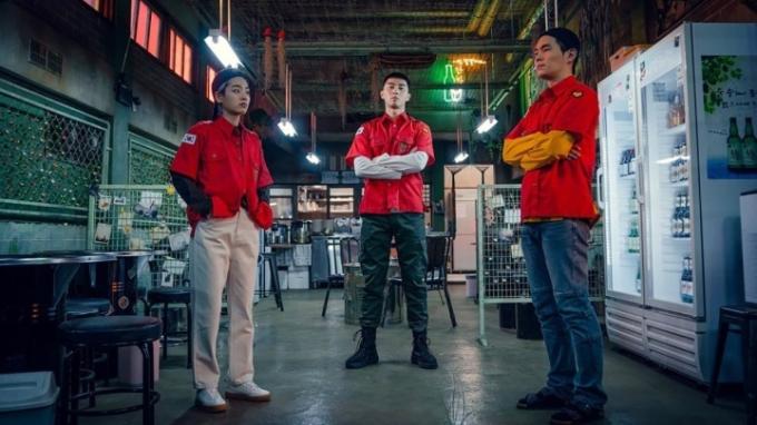 Tre man står i ett lager och tittar på en scen från Itaewon Class.