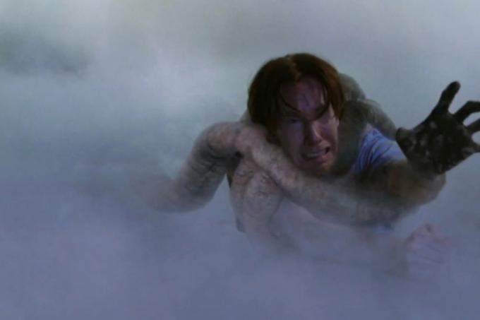 Een personage uit The Mist wordt door de tentakel van een wezen naar een mistige achtergrond getrokken.