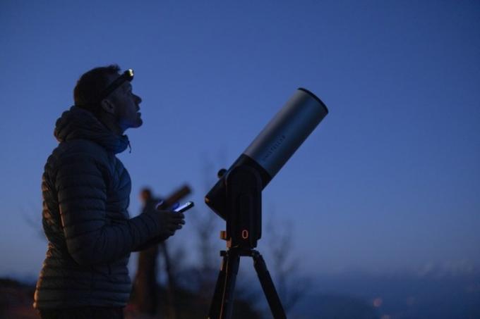 čovjek s prednjom svjetiljkom gleda u noćno nebo s teleskopom