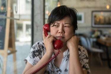 Nopietna sieviete mājās runā pa telefonu