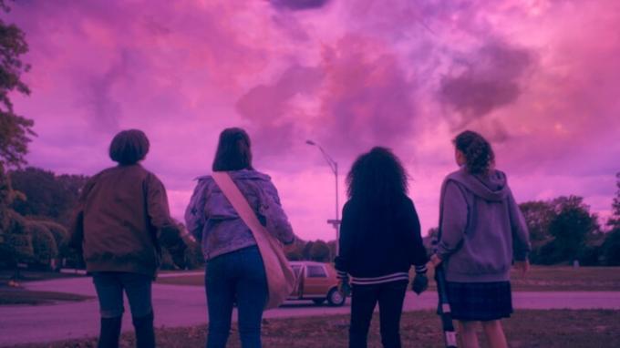 Sofia Rosinsky, Riley Lai Nelet, Camryn Jones ve Fina Strazza, Paper Girls'ten bir sahnede pembe gökyüzüne bakıyor.
