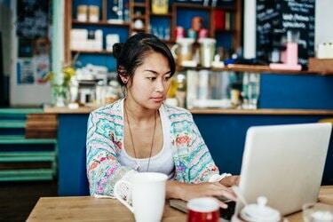 Młoda kobieta pracuje na laptopie w kolorowej kawiarni