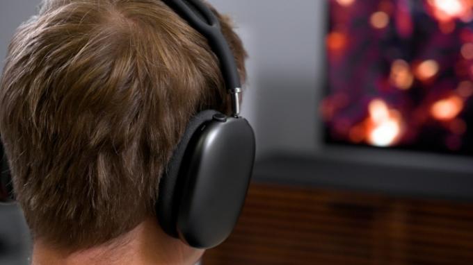 Un spectateur utilise des écouteurs AirPods Max pour découvrir Spatial Audio sur la nouvelle Apple TV 4K