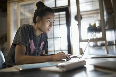 オフィスでラップトップで働く焦点を絞った若い女性