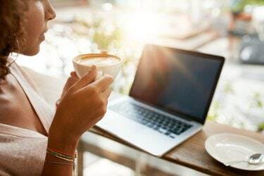 Kvinde drikker kaffe med en bærbar computer på restaurant