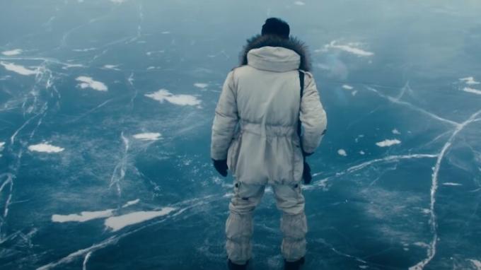 Rami Malek vilki baltą žieminį kostiumą kaip Lyutsifer Safi, stovintis ant ledo ežero