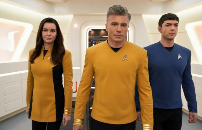 Star Trek: Strange New Worlds의 한 장면에서 Rebecca Romijn, Anson Mount, Ethan Peck이 USS Enterprise의 복도를 걷고 있습니다.