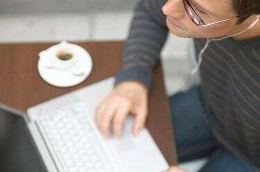 „Човек седи за столом у кафеу користећи лаптоп рачунар, крупни план”