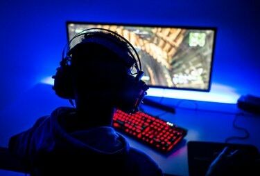 Achteraanzicht van jongen die videogame speelt op de computer in de donkere kamer