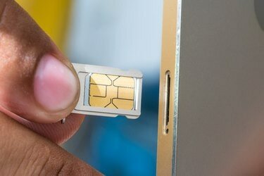 Обрезанное изображение руки, вставляющей sim-карту в мобильный телефон