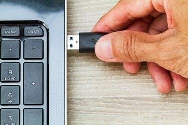 มือต่อสาย USB เข้ากับคอมพิวเตอร์แล็ปท็อปบนโต๊ะไม้