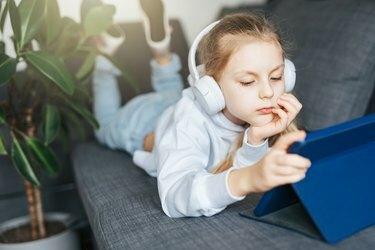 Malá holčička se sluchátky a tablet doma
