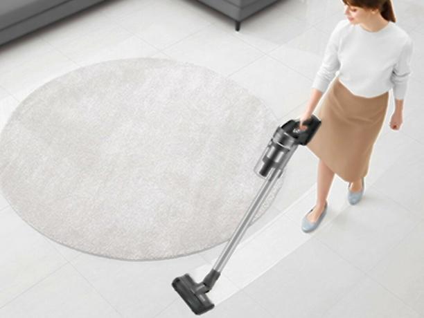 Moteris siurbia svetainės dėžę su Samsung Jet 75 Complete Cordless Stick Vacuum.