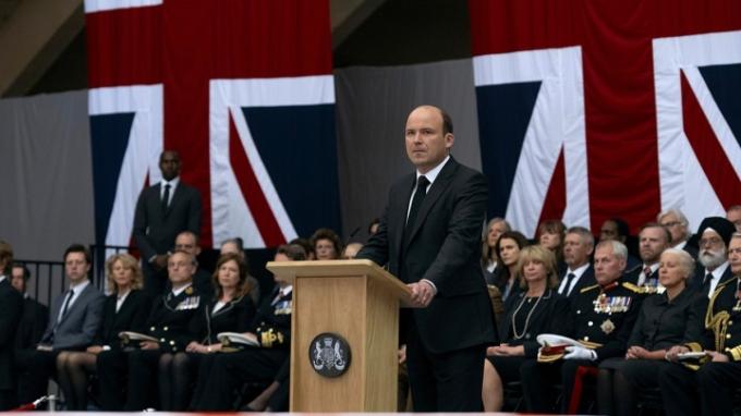 Statsminister Trowbridge står på et podium i en scene fra The Diplomat på Netflix.